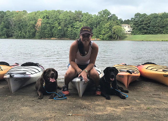 Private Training - woman sitting on a kayak near the river with two dogs, Carolina Dog Training